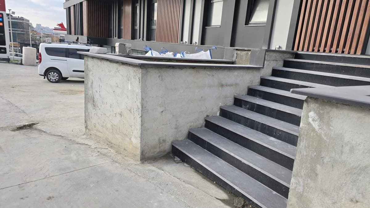 Bina girişinde koyu granit kaplı beton merdiven basamakları ve sıvalı yan duvarlar
